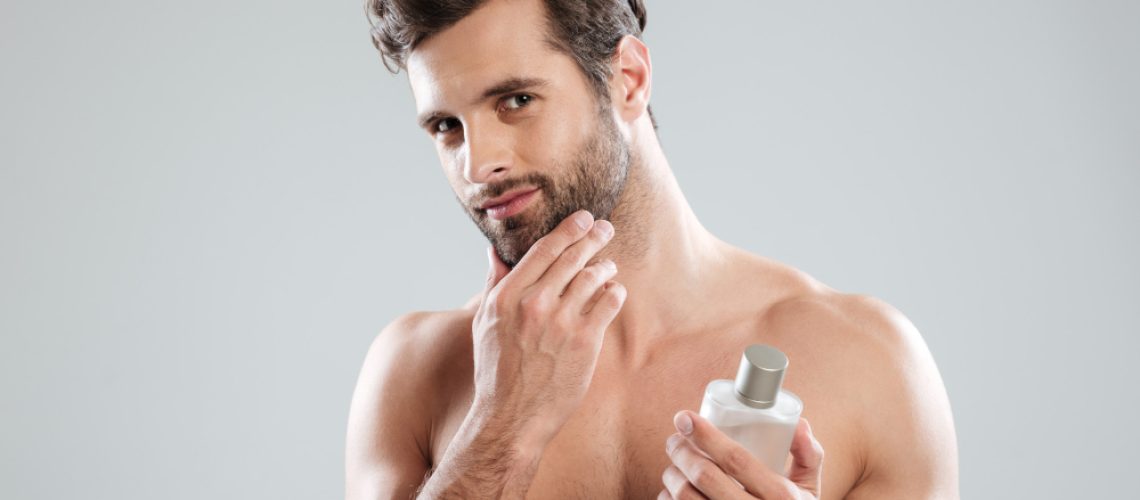 man-touching-his-face-while-holding-bottle-perfume
